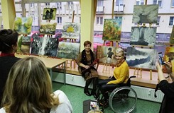 na zdjęciu artystka na tle własnych obrazów