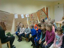Grupa przedszkolaków słucha czytanej przez bibliotekarkę książki