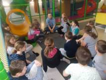Dzieci słuchają Pana, który tłumaczy zasady bezpiecznej zabawy na ślizgawkach