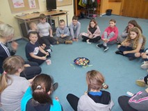 Dzieci siedą w kole na dywanie podczas wspólnej zabawy