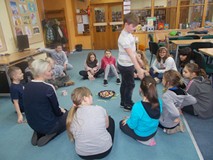 Dzieci siedą w kole na dywanie podczas wspólnej zabawy