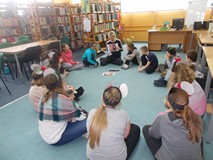 Dzieci siedzą na dywanie słuchając opowiadania