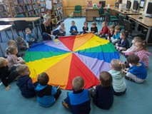 dzieci siedzą na chuście animacyjnej i słuchają bibliotekarki