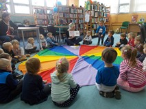 dzieci siedzą na chuście animacyjnej i słuchają bibliotekarki