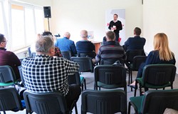 Na pierwszym planie publiczność zgromadzona na spotkaniu z Piotrem Słomskim. W tle widać autora.