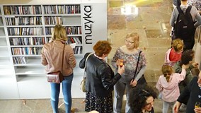 Publiczność zgromadzona na otwarciu Mediateki. Na drugim planie widać wyeksponowane zbiory i zainter