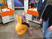 Najmłodszy uczestnik otwarcia Mediateki siedzi na siedzisku w postaci królika