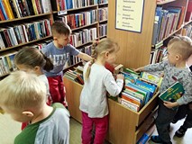 Dzieci przeglądają książeczki ze zbiorów biblioteki