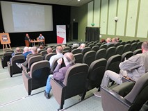Na pierwszym planie publiczność zgromadzona na spotkaniu z grzegorzem Śliżewskim. W głębi przy stoli