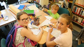 Dwie uczestniczki na pierwszym planie i jeden uczestnik projektują włoskie stroje