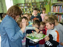 Bibliotekarka prezentuje dzieciom książkę 