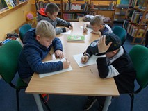 Chłopcy siedzą przy stole i rozwiązują łamigówki