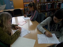 Dziewczynki  siedzą przy stole i rozwiązują łamigówki