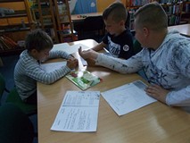 Chłopcy siedzą przy stole i rozwiązują łamigówki