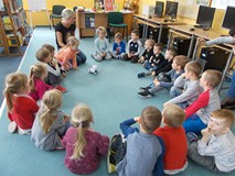 Dzieci siedzą w kole i rozmawiają z bibliotekarką