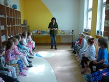 Dzieci siedzą na krzesełkach i rozmawiają z bibliotekarką o filmowych bohaterach książek
