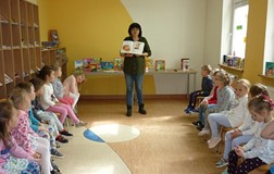 Dzieci siedzą na krzesełkach i rozmawiają z bibliotekarką o filmowych bohaterach książek