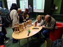 Krzysztof Varga siedzi przodem i rozdaje autografy. Wokół niego zgromadzona publiczność
