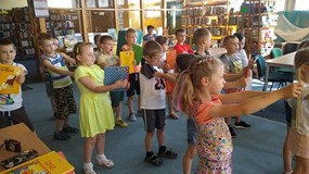 Dzieci wykonują ćwiczenia z książkami w ręku