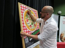 Bartek Kieżun składa pamiątkowy autograf na plakacie promującym Włoską Noc w Bibliotece