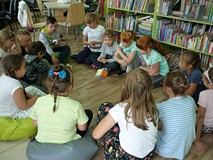 Dzieci, siedząc w kręgu bawią się w cukierkwą grę
