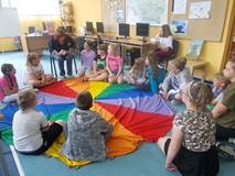 Prowadząca warsztaty prowadzi zabawę z dziećmi siedzącymi na chuście animacyjnej