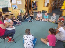 Dzieci siedzą w kole i rozmawiają z prowadzącą warsztaty o ekologii