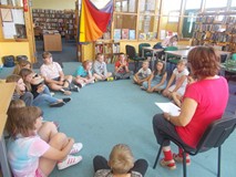 Dzieci siedzą w kole i rozmawiają z prowadzącą warsztaty o ekologii