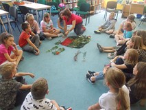 Prowadząca warsztaty rozmawia z dziećmi pokazując im liście poszczególnych drzew