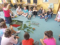 Prowadząca warsztaty rozmawia z dziećmi pokazując im liście poszczególnych drzew