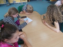 Dzieci siedzą przy stolikach podczas prac w grupach