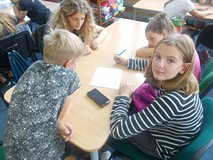 Dzieci siedzą przy stolikach podczas prac w grupach