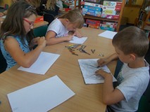 Dzieci siedzą przy stolikach podczas wykonywania pracy plastycznej