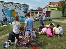 Dzieci uczestniczące w akcji tworzenia muralu segregują plastikowe nakrętki