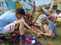 Dzieci uczestniczące w akcji tworzenia muralu segregują plastikowe nakrętki