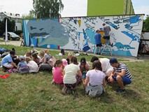 Dzieci uczestniczące w akcji tworzenia muralu segregują plastikowe nakrętki