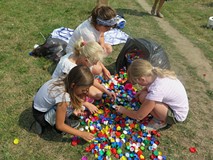 Dzieci uczestniczące w akcji tworzenia muralu segregują plastikowe nakrętki