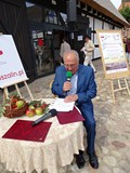 Jan Bętkowski siedzi przy stoliku i czyta podczas Narodowego Czytania 2019