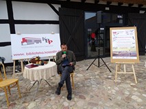 Jacek Wezgraj siedzi przy stoliku i czyta podczas Narodowego Czytania 2019