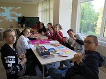 Młodzież biorąca udział w warsztatach z socjolożką Hanną Kroczak. Uczestnicy siedzą przy stoliku.