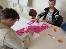 Młodzież biorąca udział w warsztatach z socjolożką Hanną Kroczak. Uczestnicy siedzą przy stoliku.