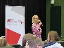 Joanna Jagiełło podczas spotkania autorskiego z młodzieżą. W tle widoczny roll-up KBP. Na przednim p