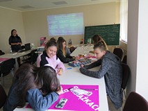 Młodzież biorąca udział w warsztatach z socjolożką Hanną Kroczak. Uczestnicy siedzą przy stoliku.
