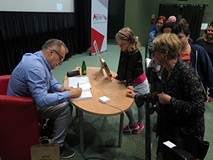 Marcin Kostrzyński rozdaje autografy po zakończonym spotkaniu w Koszalińskiej Bibliotece Publicznej.