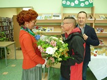 Gość wystawy wręcza artystce bukiet kwiatów