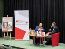 Od lewej: Plakat  promujący spotkanie z Cezarym Łazarewiczem, baner KBP, Rektor PWSZ w Koszalinie dr