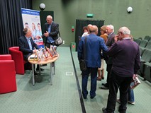 Cezary Łazarewicz siedzi przy stoliku i rozdaje autografy. Wokół niego stoi zgromadzona publiczność