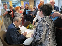 Eugeniusz Żuber składa pamiątkowe podpisy. Wokół niego stoją czytelnicy.