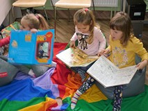 Trzy dziewczynki siedzą na podłodze i oglądają książki