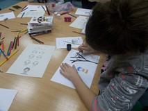 Dzieci siedzą przy stole i wykonują prace plastyczną